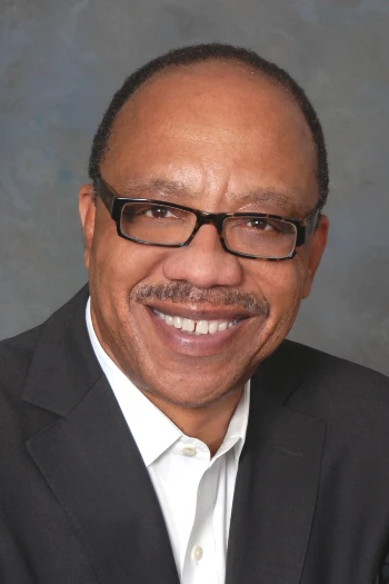Headshot of Eugene Robinson, waering a black suit with a white shirt and smiling at the camera