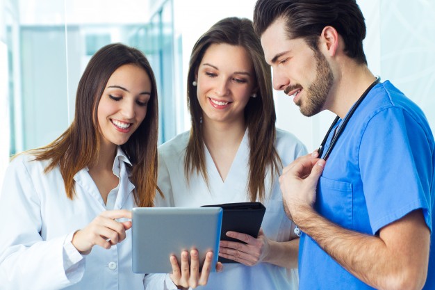 three healthcare workers or students collaborating on a tablet device