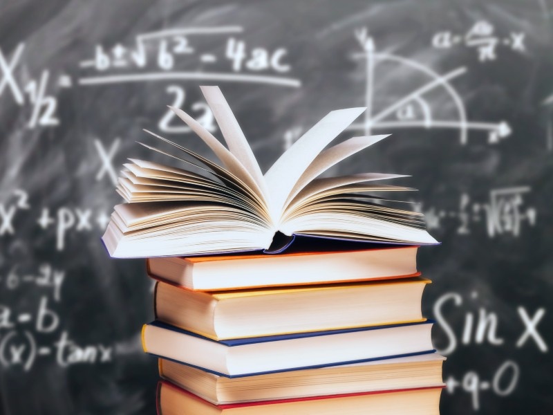A stack of books in front of a blackboard.