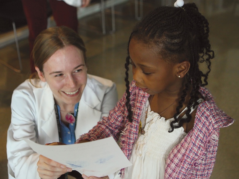 A student of family and preventative medicine at Rush University works with a young girl.